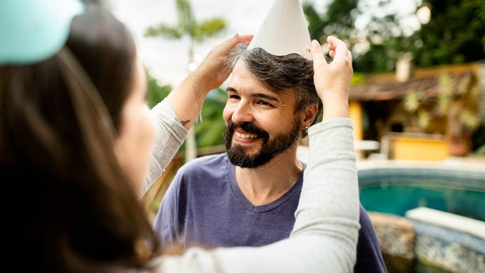 sister putting a party hat on her smiling brother for a birthday party