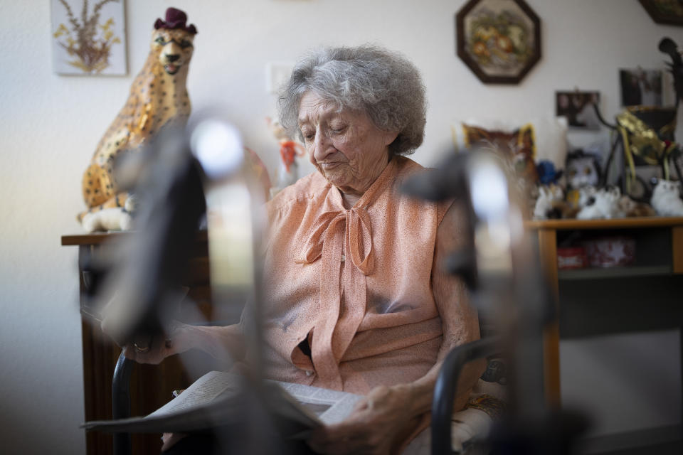 Marie Louise Kopp looks at a newspaper as she waits for a call from her son in her room at a nursing home in Ammerschwir, France Thursday April 16, 2020. In France, nursing home deaths account for more than a third of the country's total coronavirus victims — figures the government now documents meticulously after weeks of pressure. (AP Photo/Jean-Francois Badias)