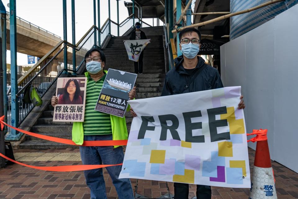 Pro-democracy activists hold placards as they show support for12 Hong Kong residents detained in mainland China and former lawyer Zhang Zhan outside the Liaison Office of the Central People’s Government on December 28, 2020, in Hong Kong (Getty Images)