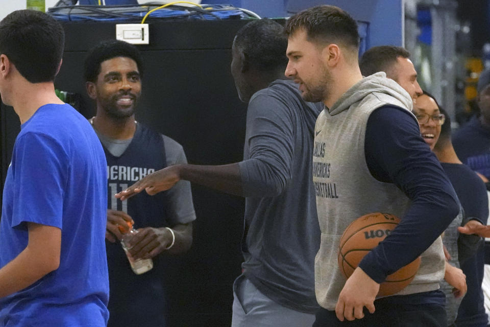 Dallas Mavericks guard Luka Doncic, right, carries a basketball as guard Kyrie Irving, left center, chats during an NBA basketball training camp in Dallas, Thursday, Sept. 28, 2023. (AP Photo/LM Otero)