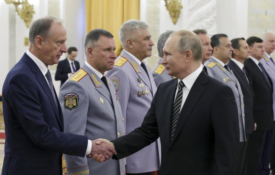 Russian President Vladimir Putin shakes hands with Russian Security Council chairman Nikolai Patrushev, left, as he greets senior military officers during a meeting in Moscow, Russia, Wednesday, Nov. 6, 2019. Putin said Russia's new weapons have no foreign equivalents but he insists the country will not use them to threaten anyone. (Mikhail Klimentyev, Sputnik, Kremlin Pool Photo via AP)