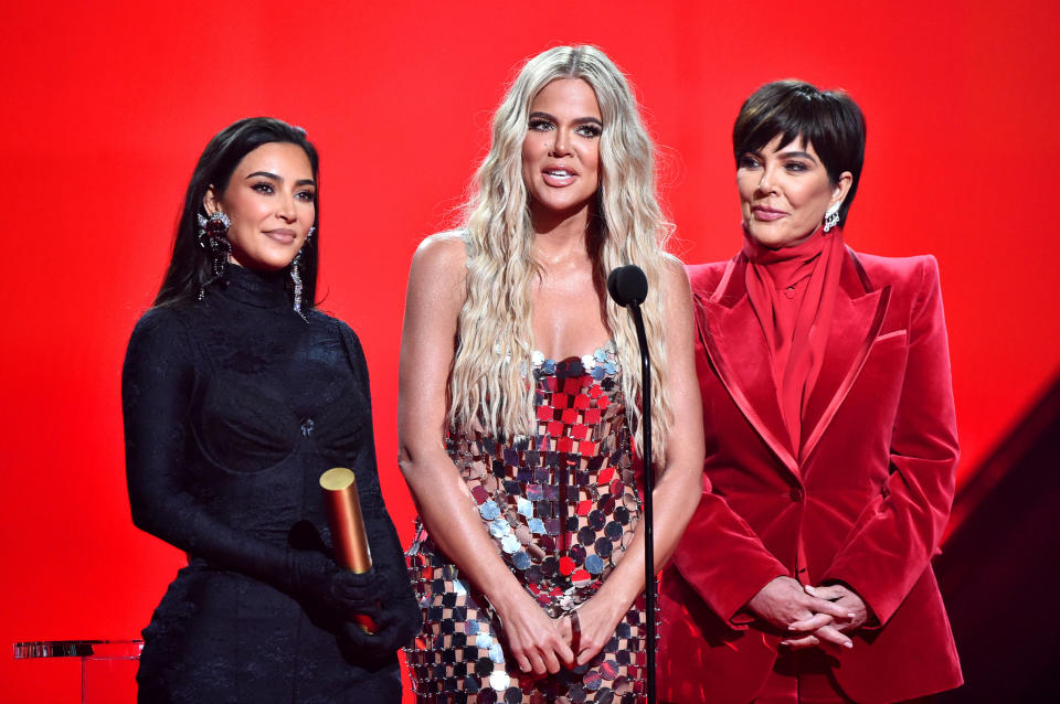 Kim, Khloe, and Kris standing on an awards stage