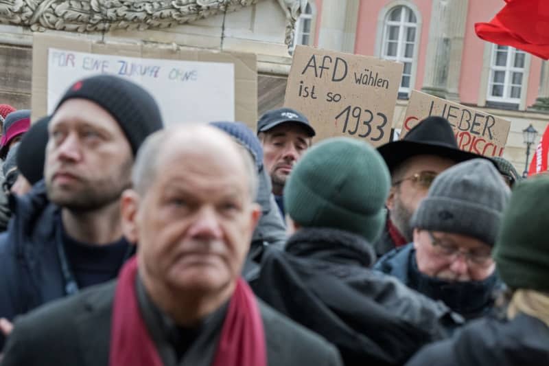German Chancellor Olaf Scholz stands on the Alter Markt as "Voting for the AfD is so 1933" words seen in a placard during the "Potsdam defends itself" demonstration in a reaction to the announcement of a meeting of right-wing activists in the city. Sebastian Christoph Gollnow/dpa