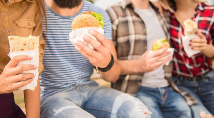 a group of people eating fast food, including cheeseburgers and fries