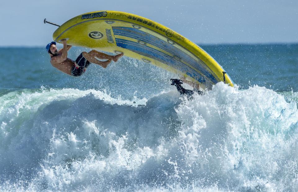 A man surfs with a goat.