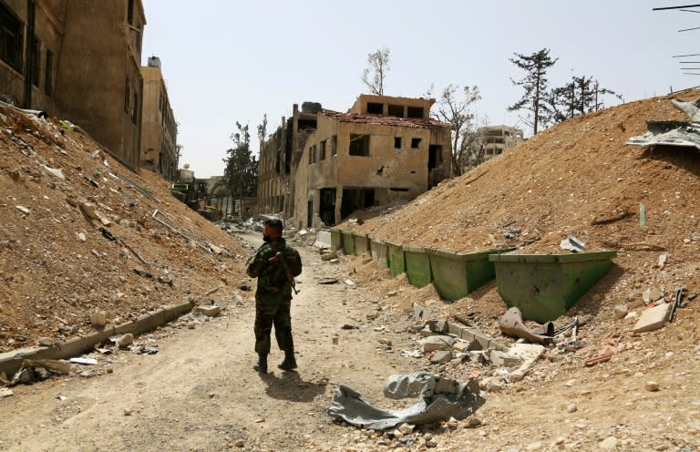 A Syrian soldier walks down a destroyed street in the former rebel-held Syrian town of Douma on the outskirts of Damascus on April 19, 2018