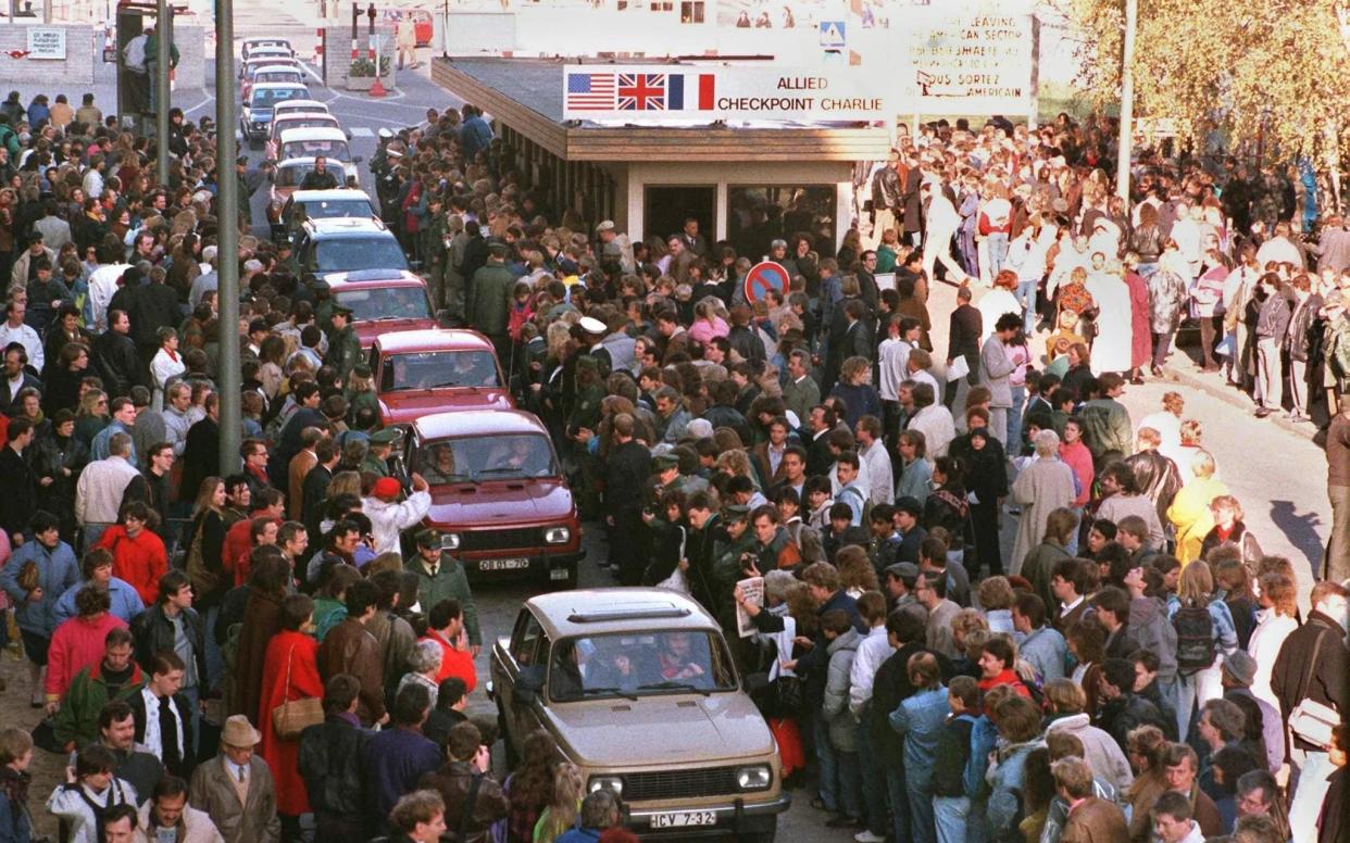 Wartburgs pass through Checkpoint Charlie to be greeted by West Berliners in November 1989 - AFP