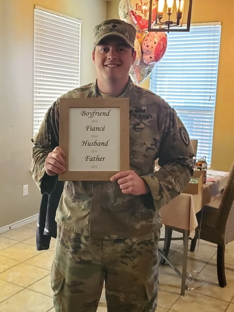 This March 20, 2019 photo, provided by Krista Johnston, shows her husband, Sgt. James Johnston, 24, with the sign she presented him announcing she was pregnant in Copperas Cove, Texas. When Krista delivered the news, tears rolled down his cheeks. "It was the first time I'd see him cry in the seven years we'd been together," she recalls. She cried, too. The next morning, he headed to war. (Krista Johnston via AP)