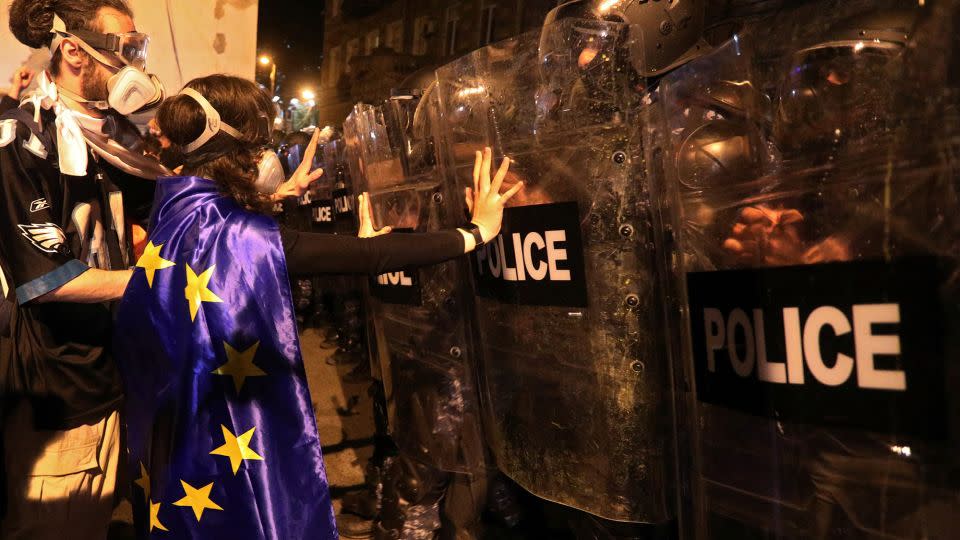 A protester draped in an European Union flag confronts riot police in Tbilisi, April 16, 2024. - Irakli Gedenidze/Reuters