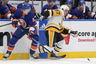 New York Islanders' Simon Holmstrom, left, and Pittsburgh Penguins' Sidney Crosby scuffle for the puck during the first period of an NHL hockey game Wednesday, April 17, 2024, in Elmont, N.Y. (AP Photo/Seth Wenig)