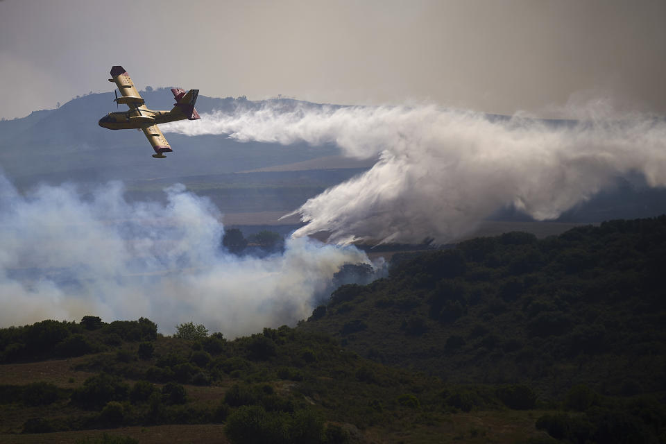 A firefight plane drops a fire retardant on a burning area of San Martin de Unx in northern Spain, Sunday, June 19, 2022. Firefighters in Spain are struggling to contain wildfires in several parts of the country suffering an unusual heat wave for this time of the year. (AP Photo/Miguel Oses)