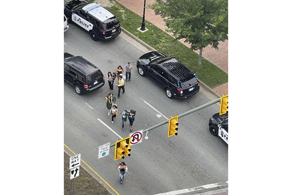 People scatter from a shooting scene as police arrive Tuesday, June 6, 2023, in Richmond, Va. Authorities in Richmond, Virginia, say seven people were shot following a high school graduation ceremony held at a downtown theater near Virginia Commonwealth University. Interim Police Chief Rick Edwards said at a news conference that two suspects were taken into custody after Tuesday's shooting. (John Willard via AP)