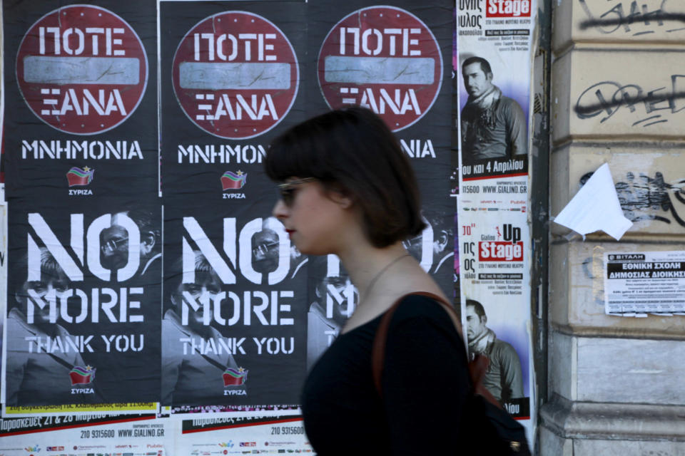 A woman walks past posters protesting a visit to Greece by German Chancellor Angela Merkel, displayed in central Athens, Friday, April 11, 2014. The left-wing main opposition party, Syriza, issued the the poster and is backing protests planned Friday. Some 5,000 police officers are on duty for Merkel's visit, that is talking place a day after Greece returned to international markets with a 5-year bond sale, following a four-year absence. (AP Photo/Dimitris Messinis)