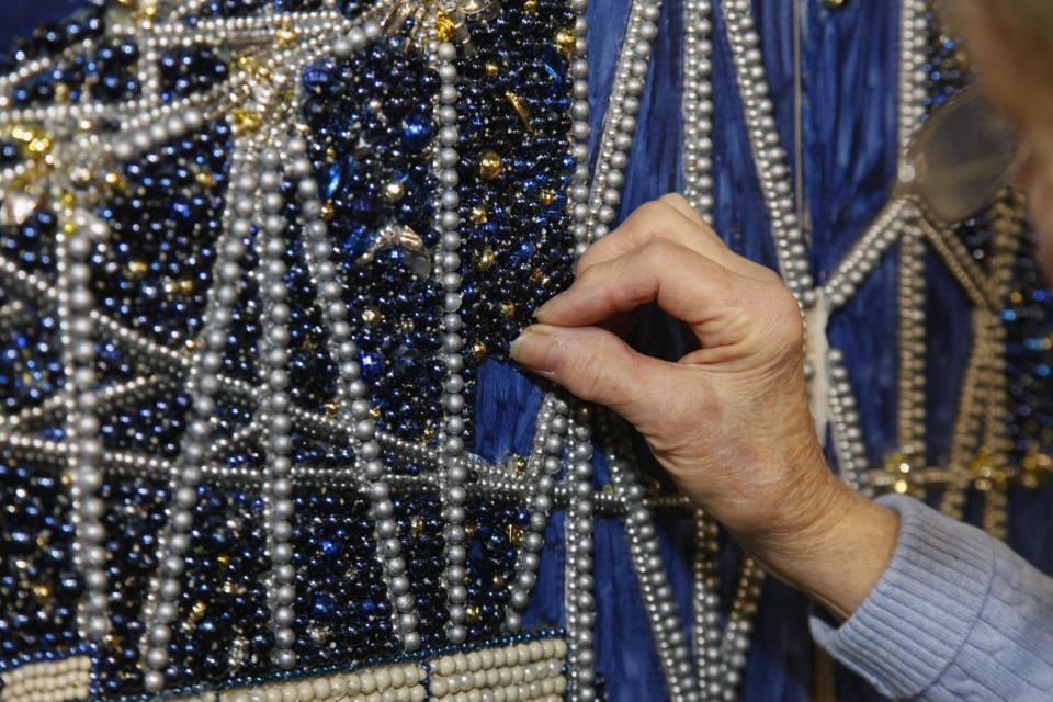 This Jan. 14, 2013 photo shows volunteer Gail Dusenberry of Clyde, North Carolina working on Artist Stephan Wanger"s bead mosaic "Paragons of New Orleans" at Mardi Gras World in New Orleans. Super Bowl takes place in New Orleans on Feb. 3 and Mardi Gras falls nine days later on Feb. 12. With both events so close together, New Orleans is bracing for a massive celebration and record crowds. (AP Photo/Bill Haber)