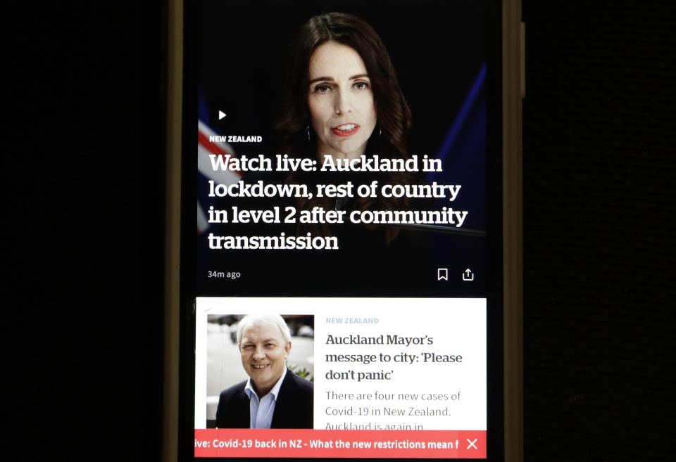 A news alert is displayed on a mobile phone in Christchurch, New Zealand, Tuesday, Aug. 11, 2020. New Zealand Prime Minister Jacinda Ardern said Tuesday that authorities have found four cases of the coronavirus in one Auckland household from an unknown source, the first cases of local transmission in the country in 102 days. (AP Photo/Mark Baker)