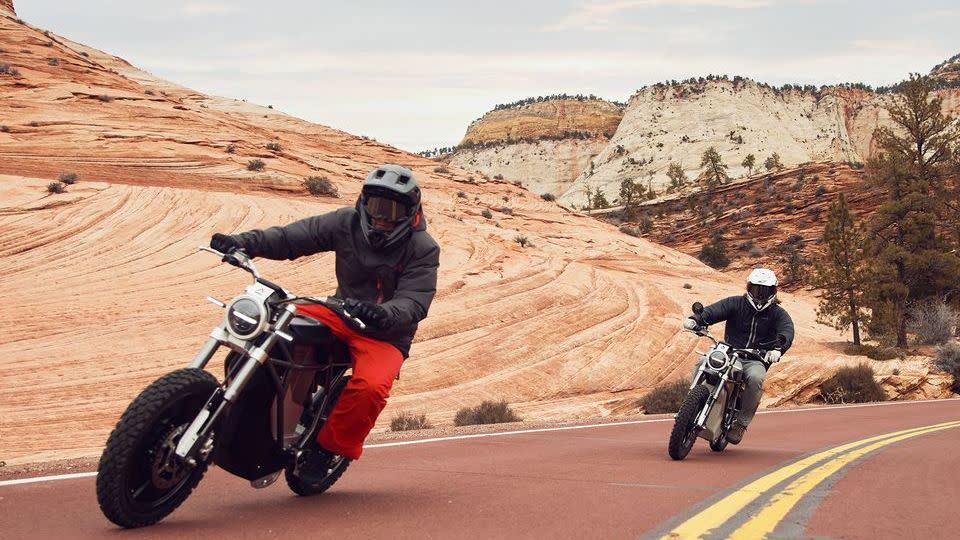 two people riding motorcycles on a road