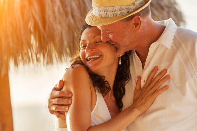 Happy Caucasian mature senior adult couple kiss on tropical beach, closeup.