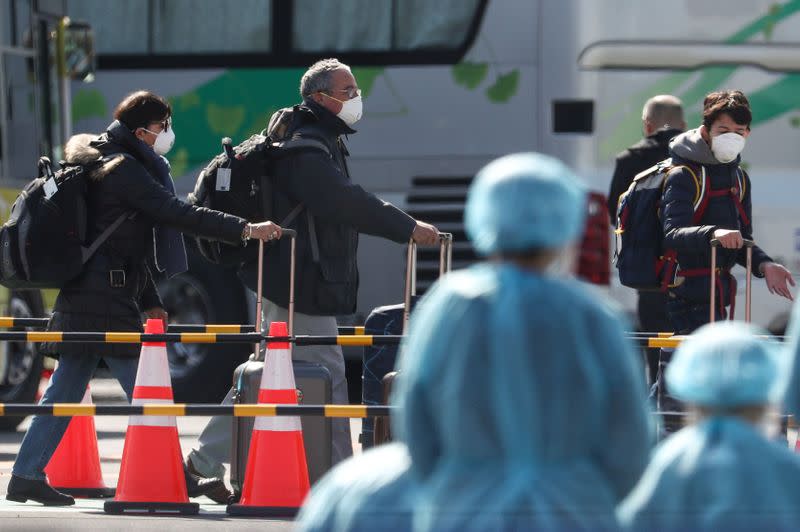 Passengers wearing masks leave cruise ship Diamond Princess at Daikoku Pier Cruise Terminal in Yokohama