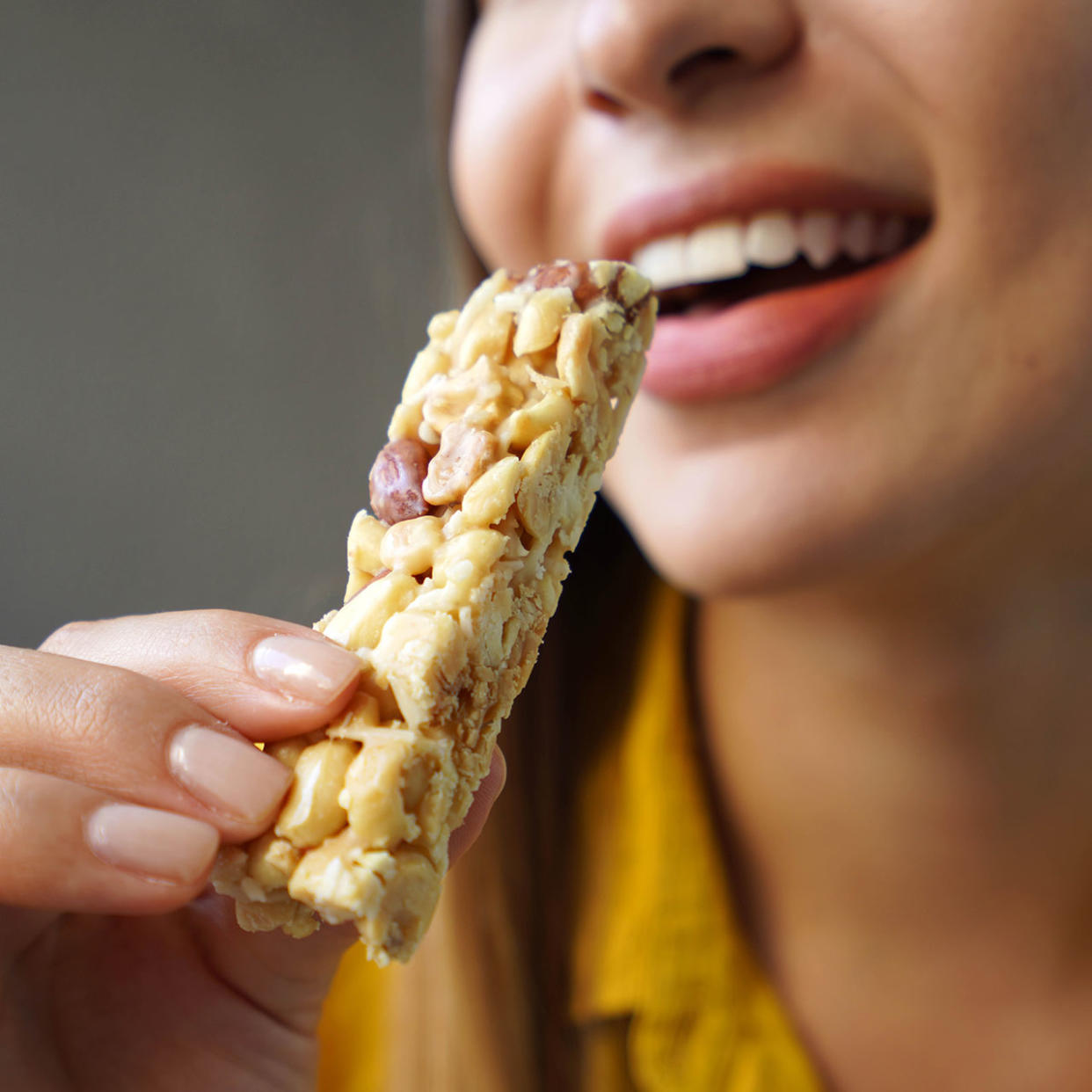 woman smiling eating granola bar
