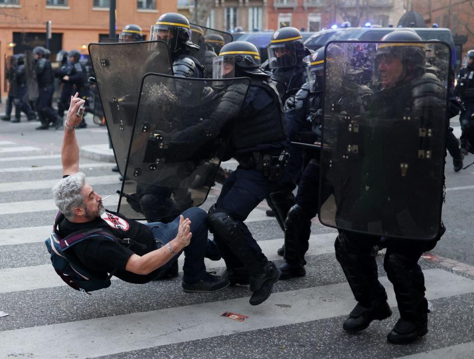 French Republican Security Corps (CRS - Compagnies Republicaines de Securite) police officers in riot gear clash with a protestor during a demonstration, a week after the government pushed a pensions reform through parliament without a vote, using the article 49.3 of the constitution, in Toulouse, southwestern France (AFP via Getty Images)