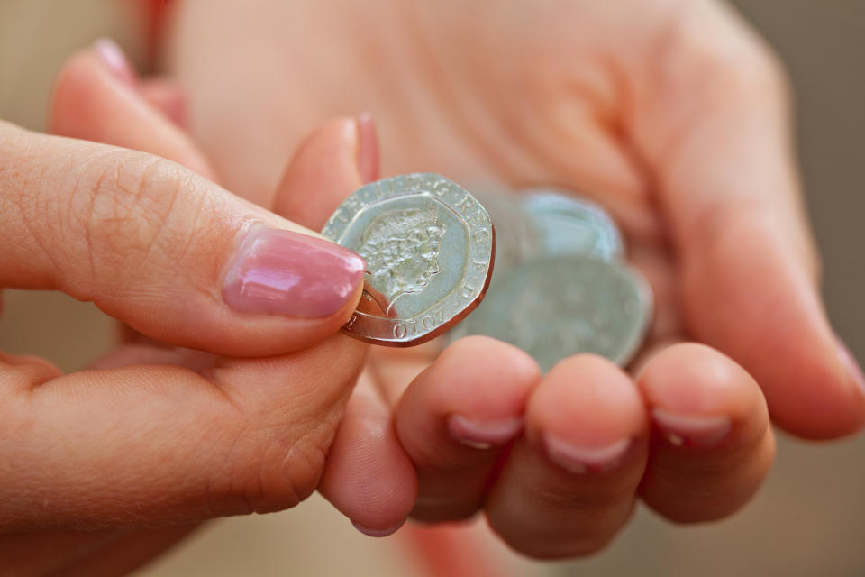 Close-up of woman’s fingers holding 20 pence coin. Photo: Getty