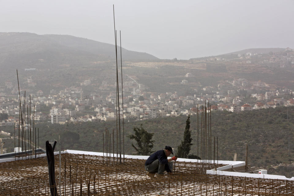 In this photo taken Monday, March 3, 2014, a worker is seen in a construction site in the Jewish settlement of Shilo. Ahmed Awais has been desperate to get out of his parents' cramped home where he, his wife and three pre-school children share one room, sleeping on mattresses on the floor at night. (AP Photo/Sebastian Scheiner)