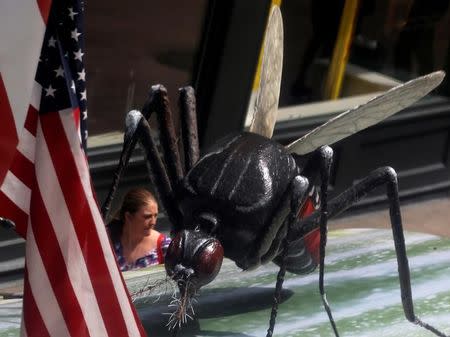 A woman walks past a giant fake mosquito placed on top of a bus shelter as part of an awareness campaign about the Zika virus in Chicago, Illinois, United States, May 16, 2016. REUTERS/Jim Young