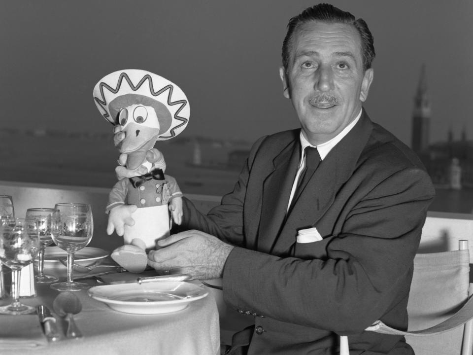 Disney sitting at a table with a donald duck doll