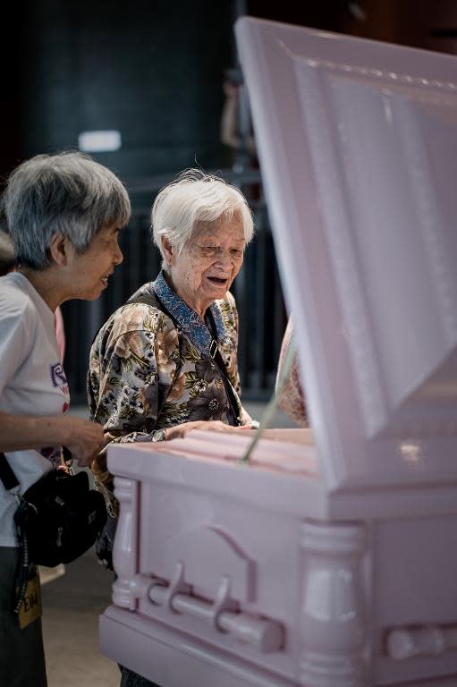 Elderly women are seen looking at a coffin displayed at an exhibition titled 'Before death and after life', in Hong Kong, on May 2, 2014
