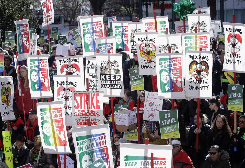 FILE - In this Thursday, Feb. 21, 2019 file photo teachers, students and supporters hold signs at Frank Ogawa Plaza in front of City Hall in Oakland, Calif. Teachers in Oakland hit the picket lines just as West Virginia teachers went back to class this week in a display of the national teacher unrest that in many places has moved beyond pay to politics, tackling issues like charter schools and vouchers. (AP Photo/Jeff Chiu,File)