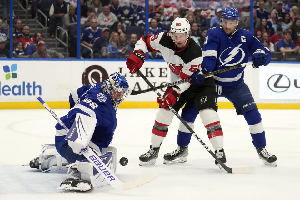 Tampa Bay Lightning goaltender Andrei Vasilevskiy (88) makes a save on a shot by the New Jersey Devils as Lightning center Steven Stamkos (91) keeps Devils' left wing Erik Haula (56) away from a rebound during the first period of an NHL hockey game Sunday, March 19, 2023, in Tampa, Fla. (AP Photo/Chris O'Meara)