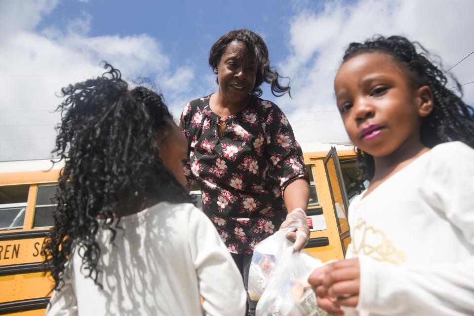 Sheledia Kelly hands food to kids as the Vicksburg Warren School District delivers meals to school aged children in Warren County, Miss., Wednesday, March 18, 2020.