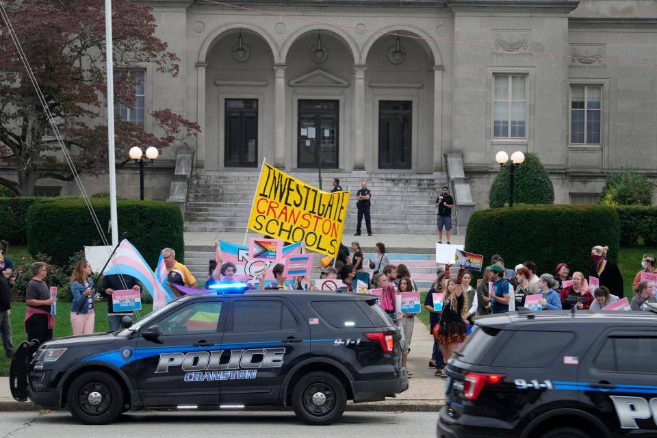 Protesters and counter-protesters gather Monday evening at the William Hall Library in Cranston, where an anti-transgender forum was underway.