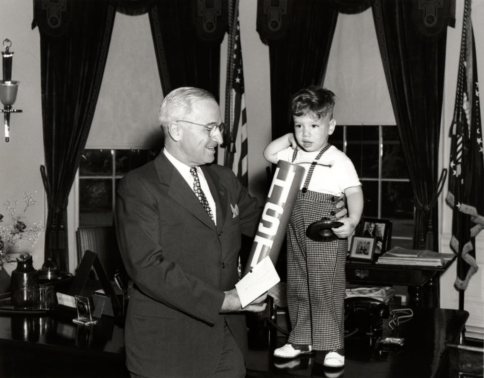 This black-and-white photograph by Abbie Rowe is of President Harry Truman meeting with Michael Gene Condatore of Washington in the Oval Office, where Michael presented the president with an oversized "firecracker" that had the president's initials on it.
