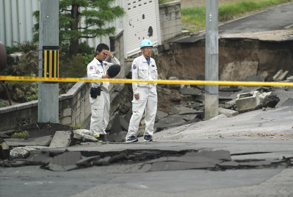 Men stand on an earthquake-damaged street in Kiyota ward of Sapporo, Hokkaido, northern Japan, Saturday, Sept. 8, 2018. Thursday's powerful earthquake hit wide areas on Japan's northernmost main island of Hokkaido. Some parts of the city were severely damaged, with houses atilt and roads crumbled or sunken. A mudslide left several cars half buried, and the ground subsided in some areas, leaving drainpipes and manhole covers protruding by more than a meter (yard) in some places. (AP Photo/Eugene Hoshiko)
