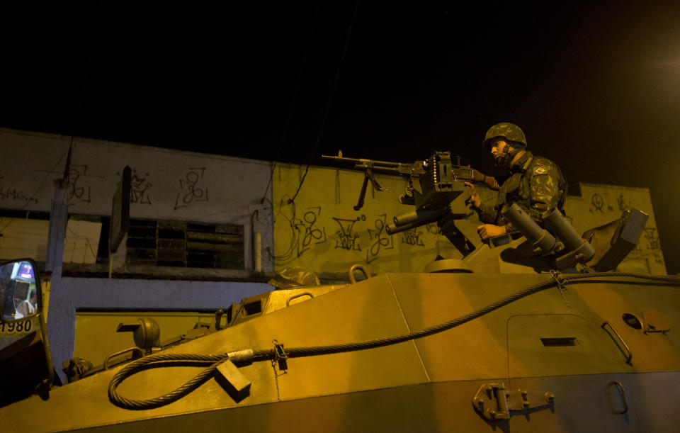 An Army soldier takes position during an operation to occupy the Mare slum complex in Rio de Janeiro, Brazil, Saturday, April 5, 2014. More than 2,000 Brazilian Army soldiers moved into the Mare slum complex early Saturday in a bid to improve security and drive out the heavily armed drug gangs that have ruled the sprawling slum for decades. (AP Photo/Silvia Izquierdo)