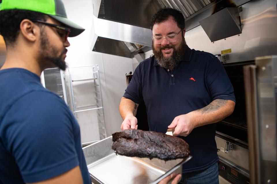 The Humble Hog owner Benjamin Grice, right, takes a brisket out of one of the restaurant's smokers on Friday, Jan. 26, 2024.