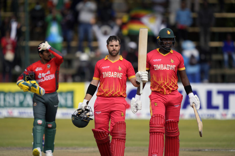 Zimbabwe's batsman Ryan Burl, centre, celebrates after scoring 50 runs on the final day of the T20 match between Zimbabwe and Bangladesh at Harare Sports Club in Harare, Zimbabwe, Tuesday, Aug. 2, 2022. (AP Photo/Tsvangirayi Mukwazhi)