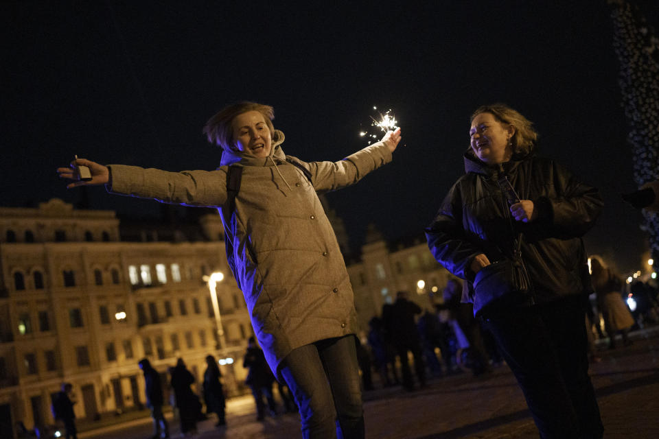 A woman holds a sparkler as she dances in Sophia Square before curfew on New Year's Eve in Kyiv, Ukraine, Saturday, Dec. 31, 2022. Multiple blasts rocked the capital and other areas of Ukraine on Saturday. (AP Photo/Roman Hrytsyna)