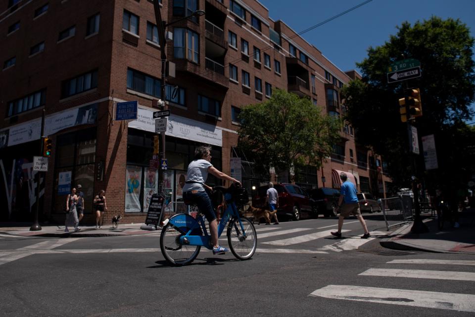 A bicyclist and pedestrians cross the intersection of South and 3rd Streets in Philadelphia, Pennsylvania, on June 5, 2022, the day after a mass shooting left three people dead and multiple people injured. - Three people were killed and 11 others wounded late on June 4, 2022, in the US city of Philadelphia after multiple shooters opened fire into a crowd on a busy street, police said.