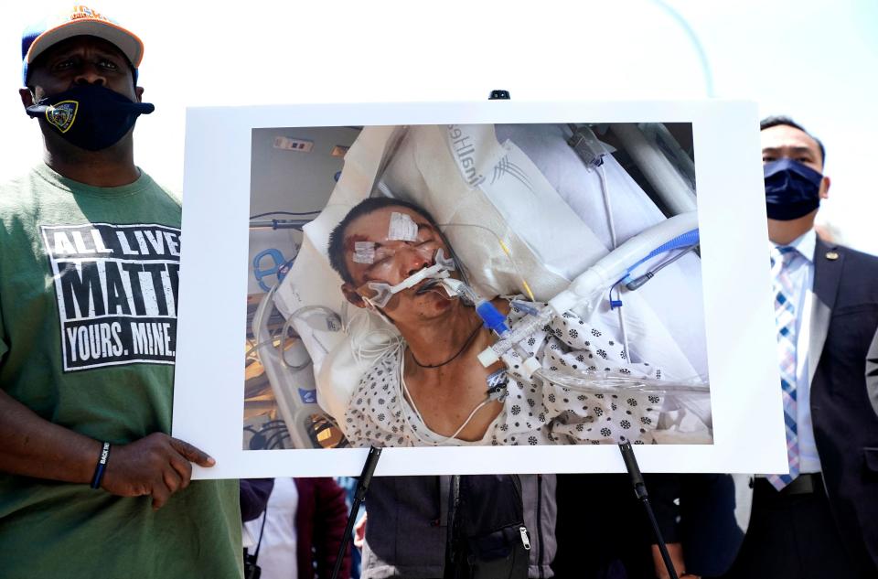 People hold a photo of  61-year old Yao Pan Ma on April 27, 2021, in New York City. Ma suffered a brain injury after being brutally attacked on April 23, 2021, on a street corner in Harlem. He died from his injuries about eight months later.  / Credit: Timothy A. Clary/AFP via Getty Images