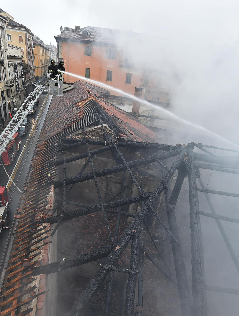 Firefighters put out a fire on the rooftop of the Cavallerizza Reale, in Turin, northern Italy, Monday, Oct. 21, 2019. A big fire broke out on Monday at Turin's Cavallerizza Reale, a historic building in the centre of the northern city which has UNESCO World Heritage status thanks to its special architectural features, no injuries were reported. (Alessandro Di Marco/ANSA via AP)