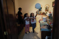 Jose Juan Serralde's daughters play in the room where his parents lived until their deaths in May from COVID-19, in San Gregorio Atlapulco, Xochimilco, Mexico City, Wednesday, July 29, 2020. Mexico recommended people self-quarantine starting in mid-March, but the elderly couple continued visiting markets to sell the plants they grew in a greenhouse, and they did not wear masks, while the family continued to live in tight quarters where most of the family got COVID-19, but recovered. (AP Photo/Rebecca Blackwell)