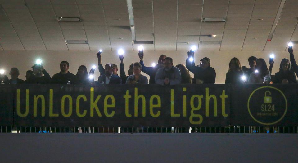 Fans hold up their cell phones and light up the darkened Chase Fieldhouse as Chris Locke describes the aims of the SL24: Unlocke the Light Foundation before Saint Mark's 67-54 win in the SL24 Memorial Classic, Friday, Feb. 2, 2024.