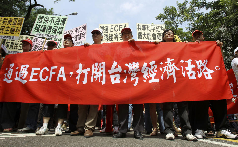 Supporters of the Economic Cooperation Framework Agreement (ECFA), recently signed with China, rally with placards that read "ECFA will save Taiwan's Economy" Wednesday, Aug. 18, 2010, in Taipei, Taiwan. Taiwan's legislature voted late Tuesday to approve the pact seven weeks after the signing of the economic agreement by the two governments. The pact slashes tariffs on hundreds of Chinese and Taiwanese products and provides Taiwanese firms with access to banking and insurance markets in China. (AP Photo/Wally Santana)