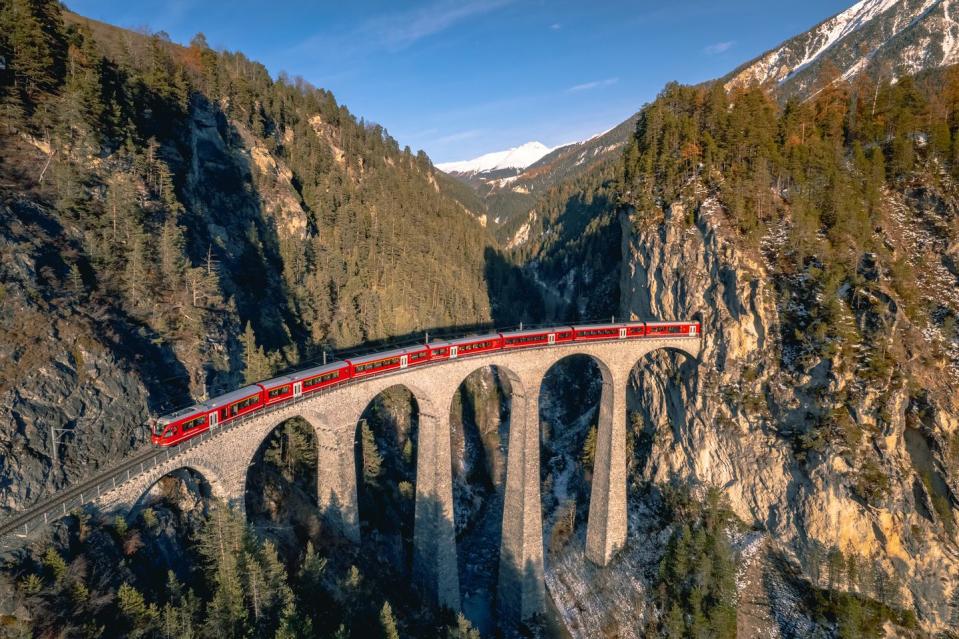 a train passing along the famous landwasser railway, famous for the viaduct and beautiful scenery surrounding the railway in the switzerland mountains