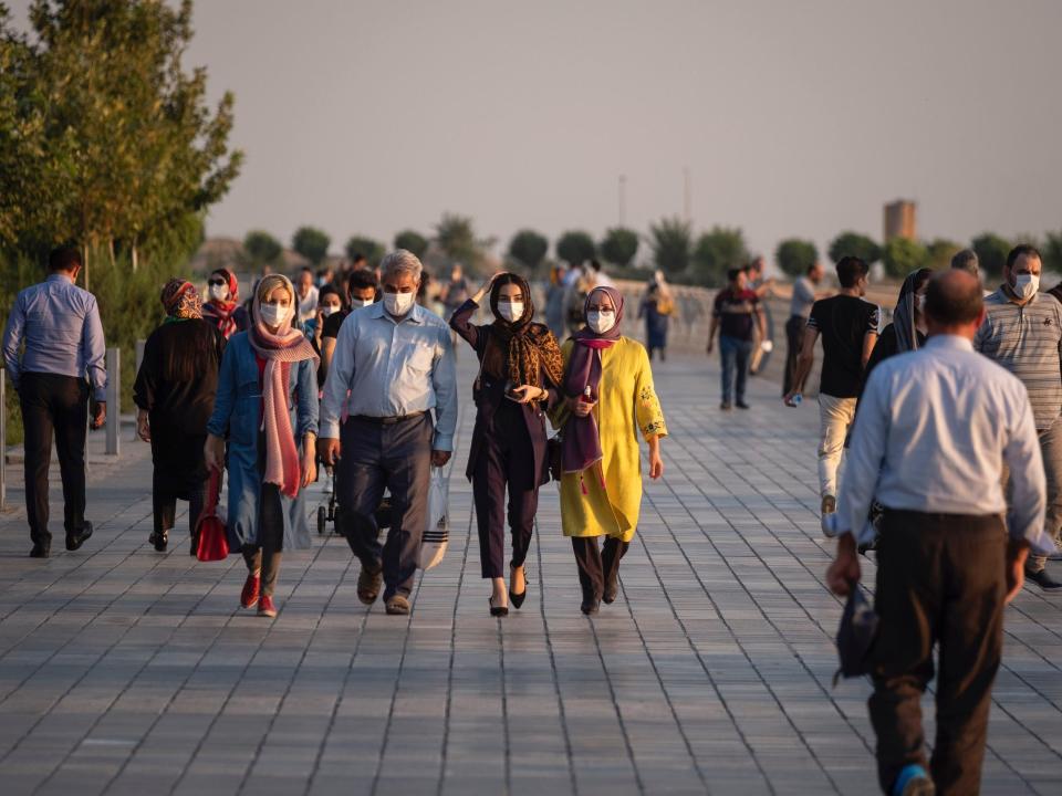 An Iranian family wearing protective face masks walk along an area in the recreational Chitgar complex in northwestern Tehran at sunset, following the COVID-19 outbreak in Iran, August 13, 2020. People living in Tehran seem to be accustomed to the new coronavirus and use the mask as a daily routine. (Photo by Morteza Nikoubazl/NurPhoto via Getty Images)