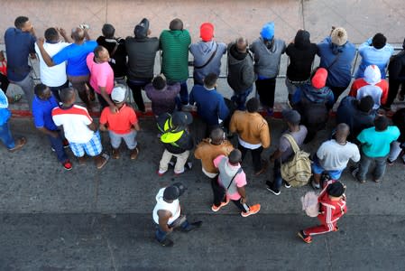 Migrants wait to apply for asylum in the United States outside the El Chaparral border in Tijuana