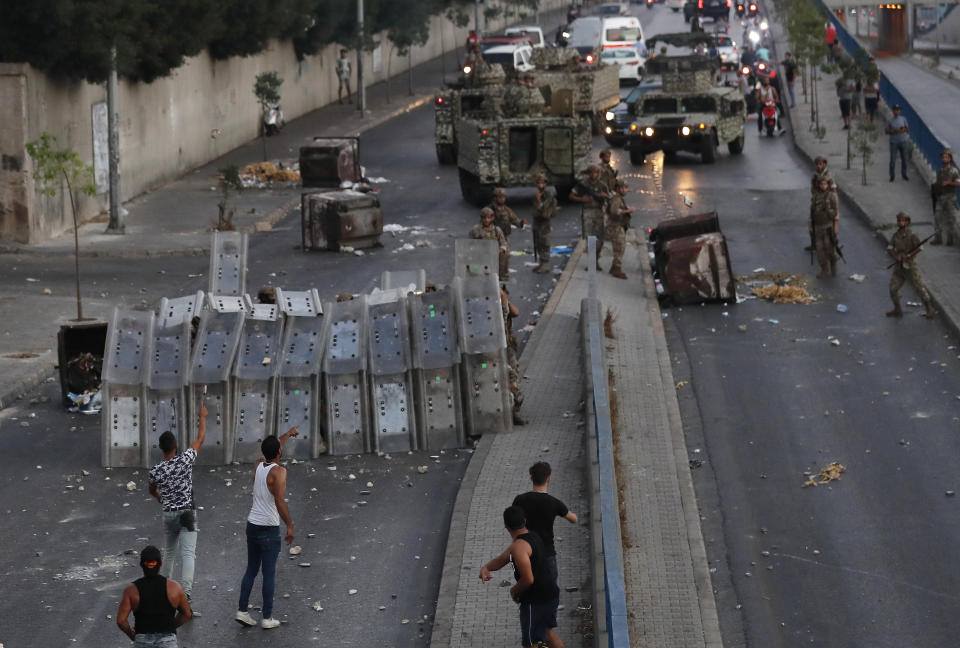 Supporters of Prime Minister-designate Saad Hariri who stepped down on Thursday, clashes with Lebanese soldiers who some them hide behind their protective shield, in Beirut, Lebanon, Thursday, July 15, 2021. Hariri says he is stepping down, nine months after he was named to the post by the parliament. He is citing "key differences" with the country's president, Michel Aoun. (AP Photo/Hussein Malla)