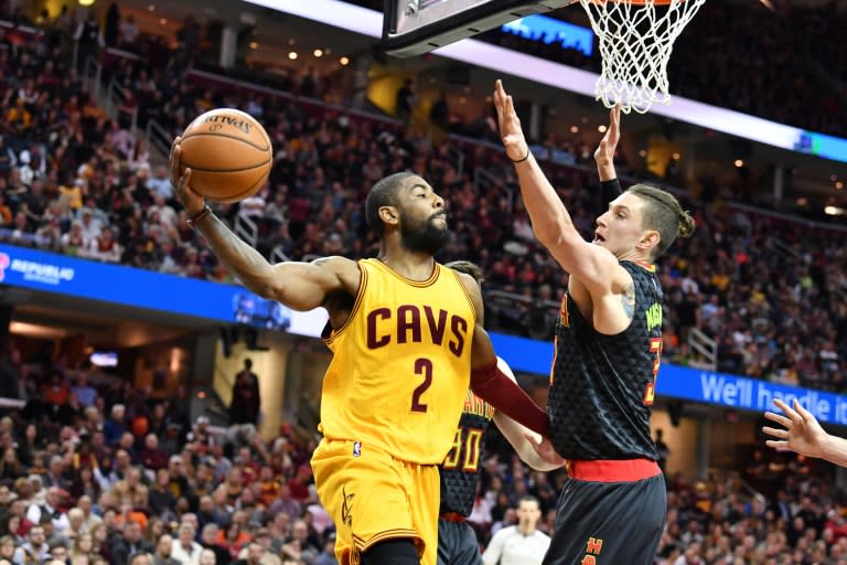 Kyrie Irving of the Cleveland Cavaliers passes around Ryan Kelly of the Atlanta Hawks during the first half at Quicken Loans Arena in Cleveland, Ohio